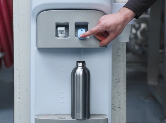Hand tapt water uit een moderne dispenser met blauwe verlichting