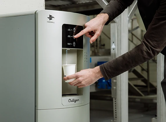 Zakenvrouw vult een glas water bij de waterdispenser op kantoor
