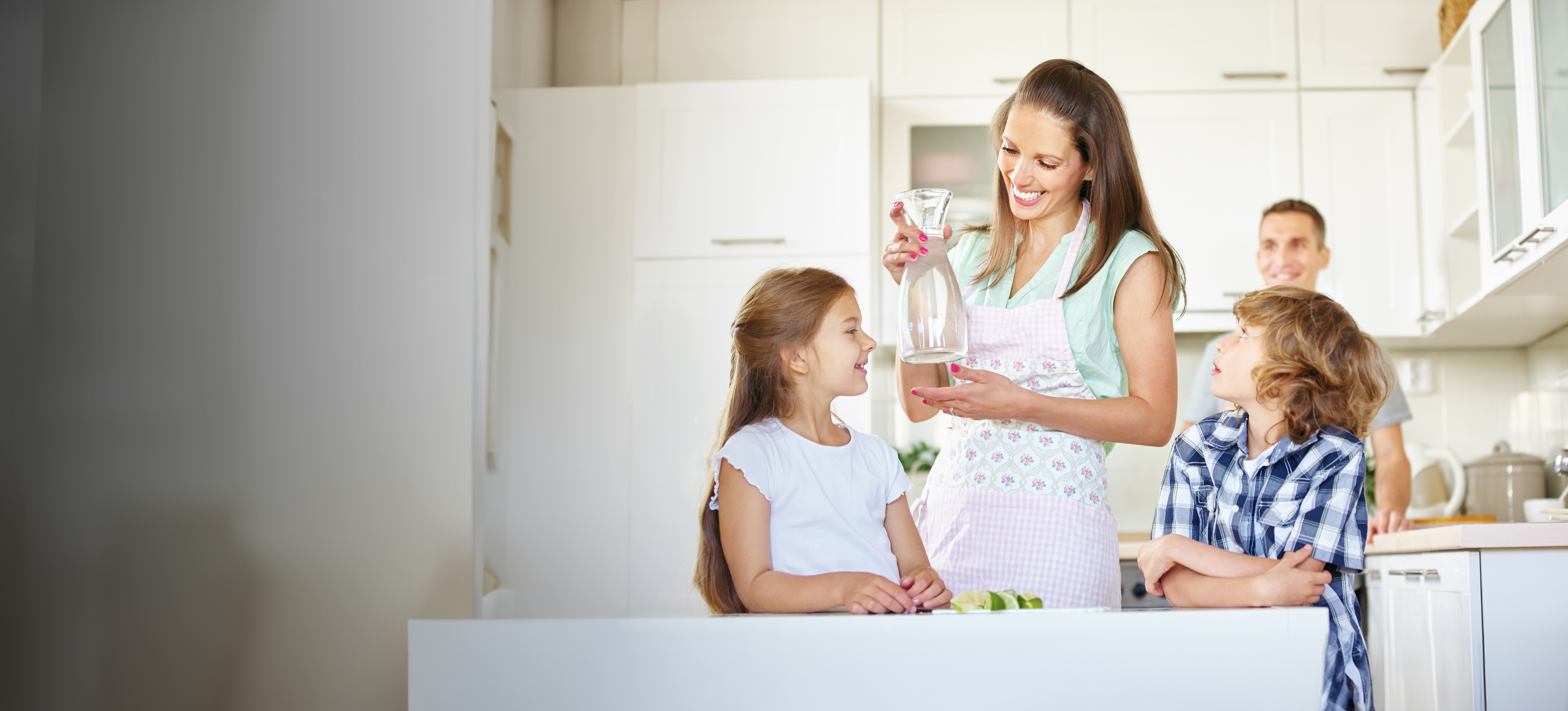 Mother,And,Children,With,Carafe,Water,In,The,Kitchen